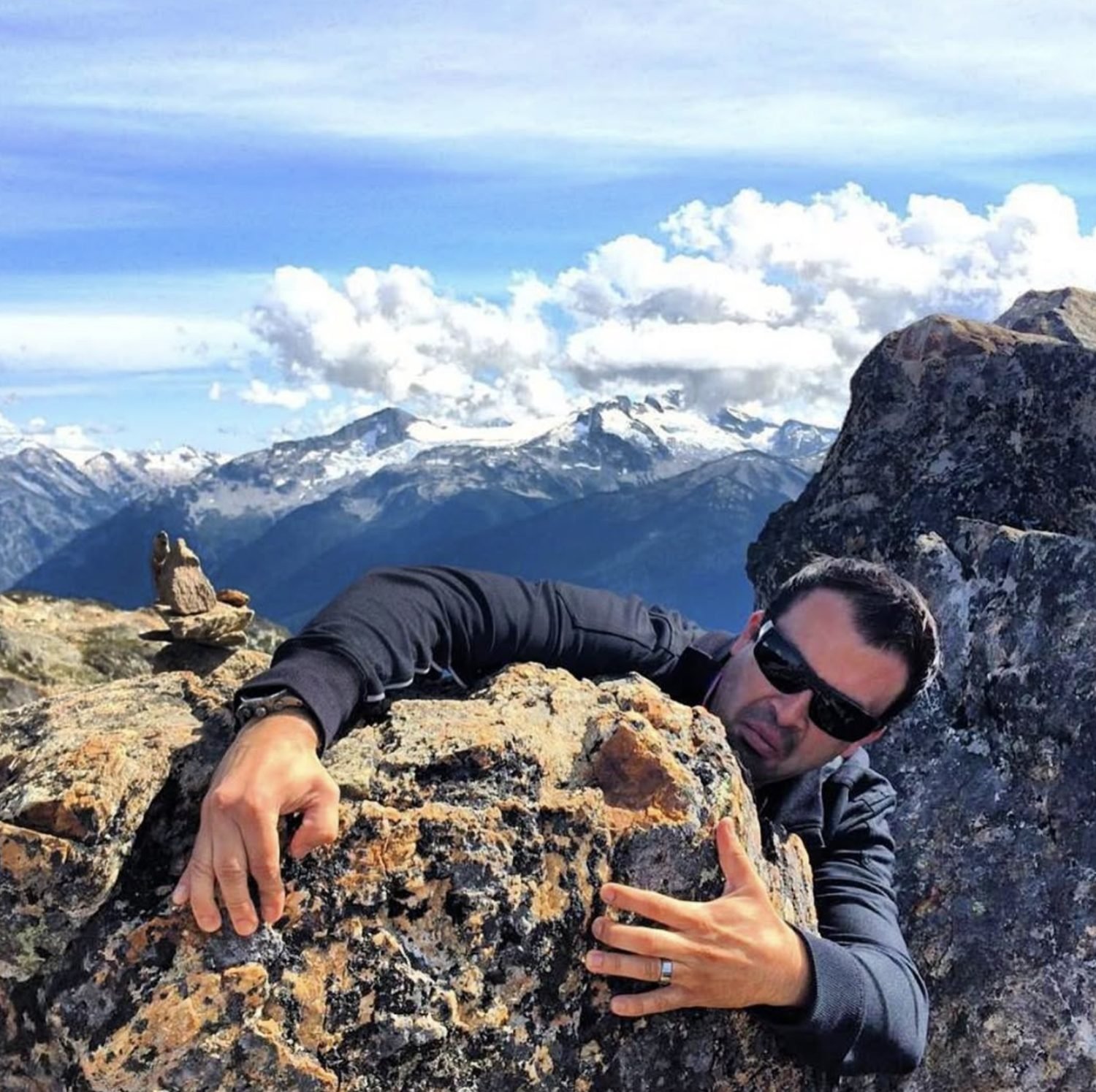 Holding onto a summit boulder in the mountains